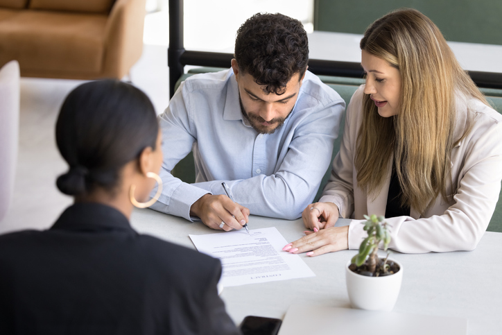happy couple signing a document in lawyer's office
